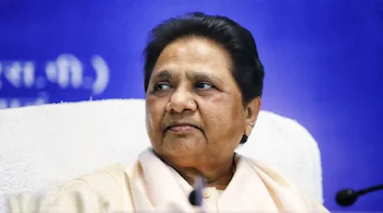 Mayawati speaking at a press event with BSP banner in background, addressing Dalit community on SP issue