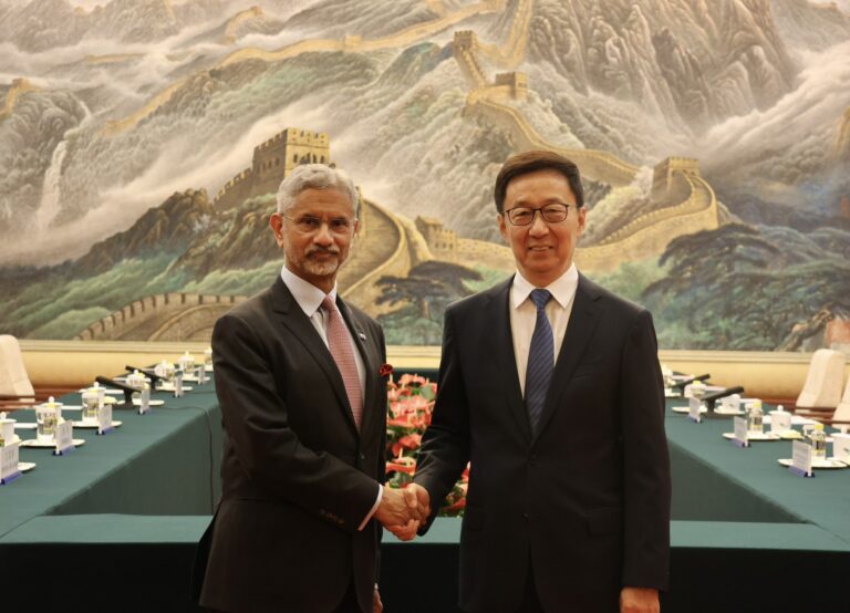 S. Jaishankar shakes hands with Chinese VP Han Zheng in Beijing, with Tibet flag, Galwan Valley, and Dalai Lama icons in the background | Shah Times