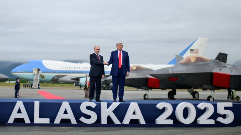 Vladimir Putin and Donald Trump shaking hands at Alaska 2025 summit with Air Force One and fighter jets visible on runway – Shah Times.