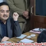 Senior health official seated at a desk during an inspection inside a clinic office in Bijnor; interaction scene captured indoors.