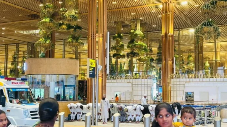 Passengers offering group prayer inside Bengaluru Airport Terminal 2 near the departure area, with airport staff and travellers visible in the background.